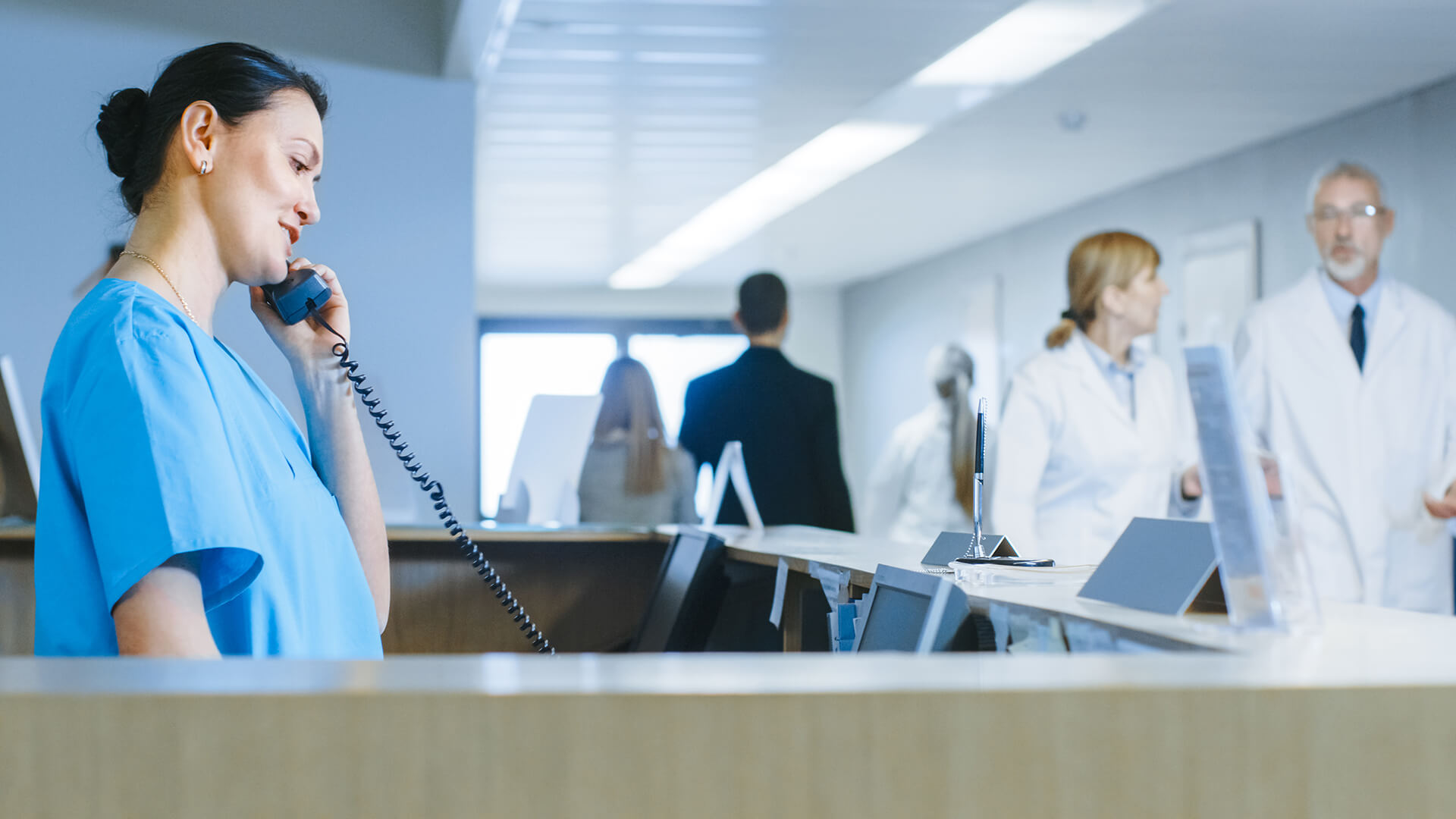 Verpleegkundige aan de telefoon bij de balie van een ziekenhuis